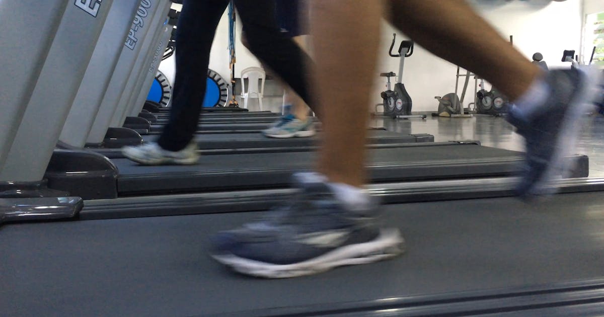 Runners' feet on a row of treadmills in a busy gym
